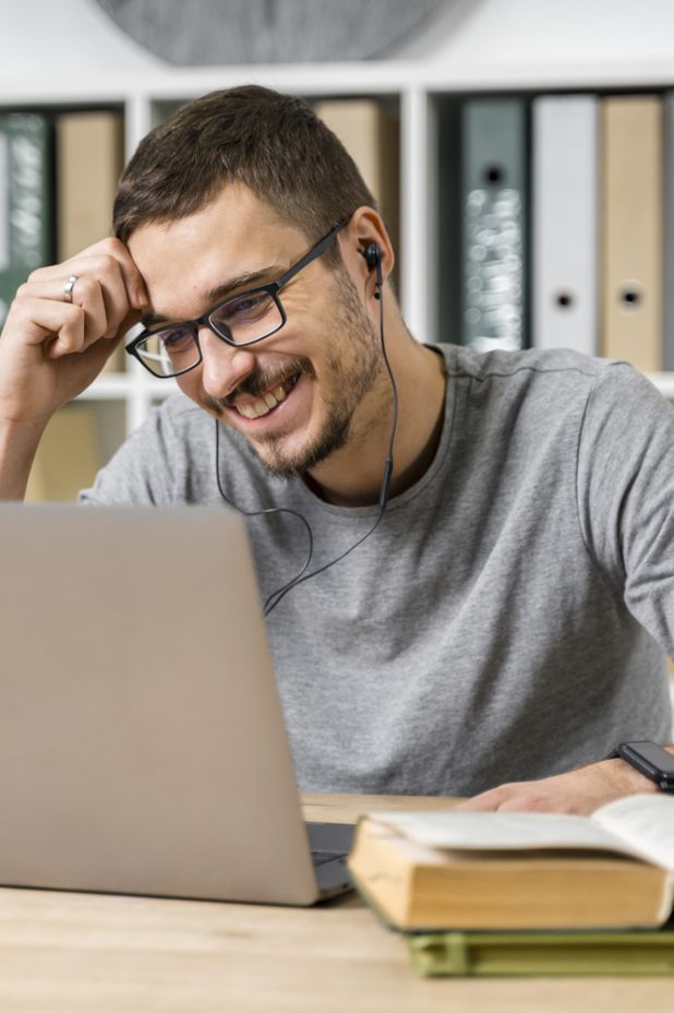 medium-shot-smiley-guy-studying-with-his-laptop (1)